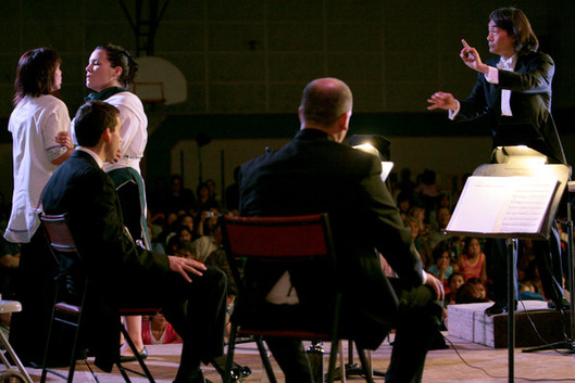Kent Nagano donne le signal aux chanteuses de gorge Evie Mark et Taqralik Partridge pendant la représentation à Inukjuak du morceau Take the Dogsled d'Alexina Louie, le 12 septembre.